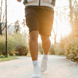 a person running on a trail with the sun beaming behind them