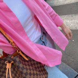 a person walking with a pink shirt and a purse on the shoulder